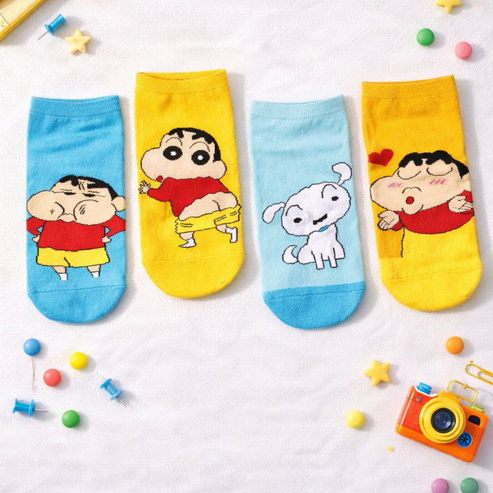 Four colorful shinchan socks with cartoon characters on a light gray background with toys around.